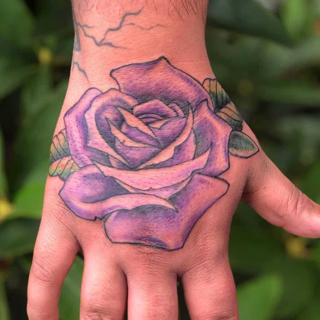 A vibrant purple rose tattoo with lush green leaves adorns a person's hand
