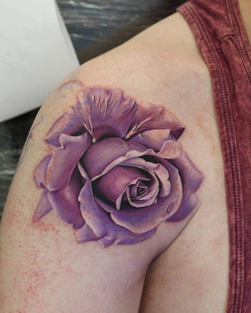 Realistic purple rose shoulder tattoo with intricate shading and petal details, placed on the upper arm.