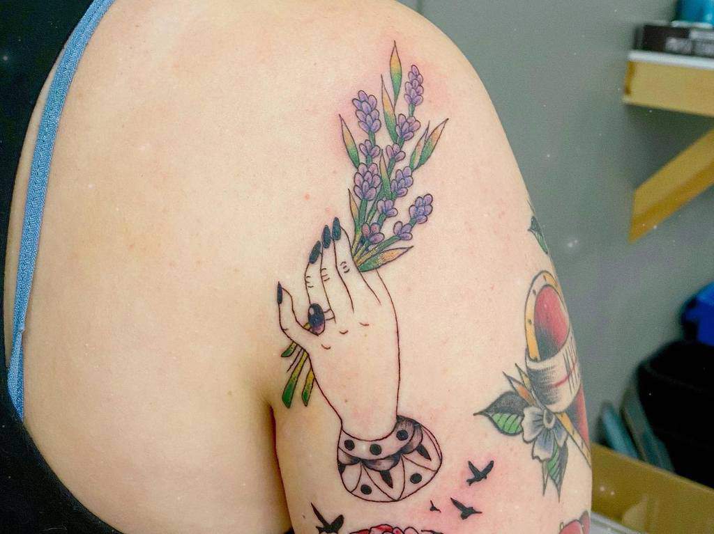 Tattoo of a hand holding lavender on an upper arm