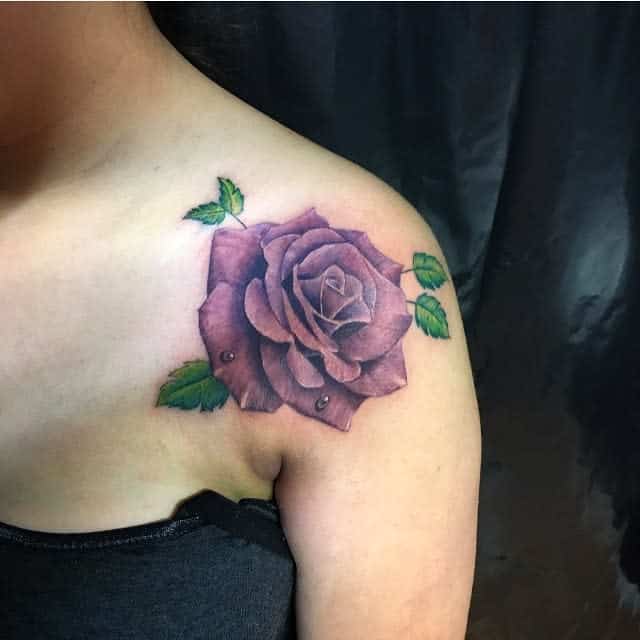 A vibrant purple rose tattoo on a shoulder