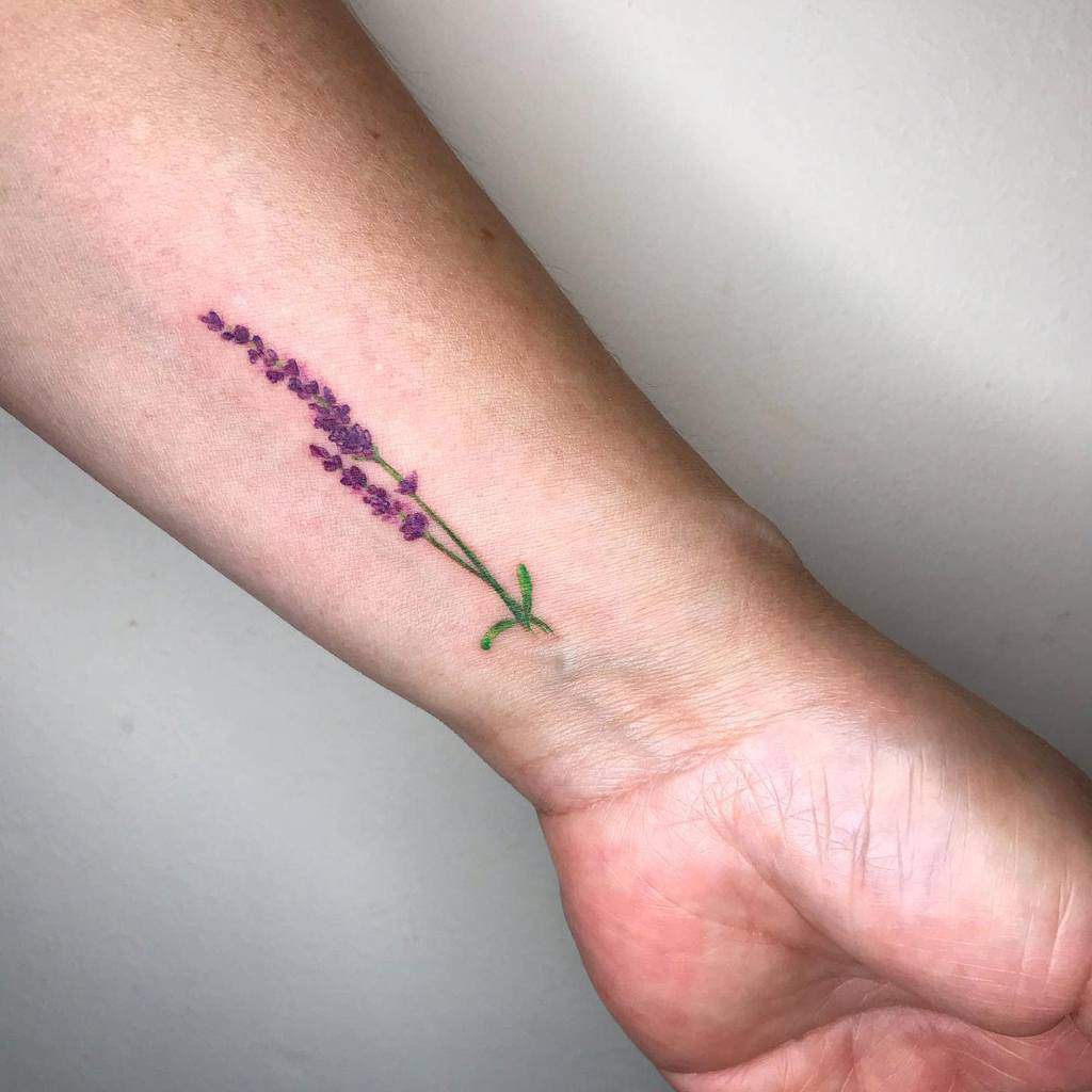 A realistic lavender tattoo on a wrist, with purple flowers and green stem