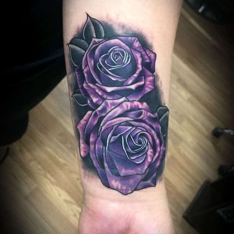 Tattoo of two purple roses with black leaves on a wrist