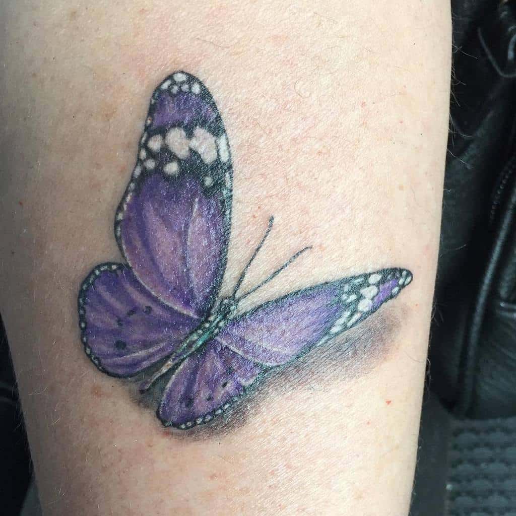 Tattoo of a purple butterfly with white accents on a forearm