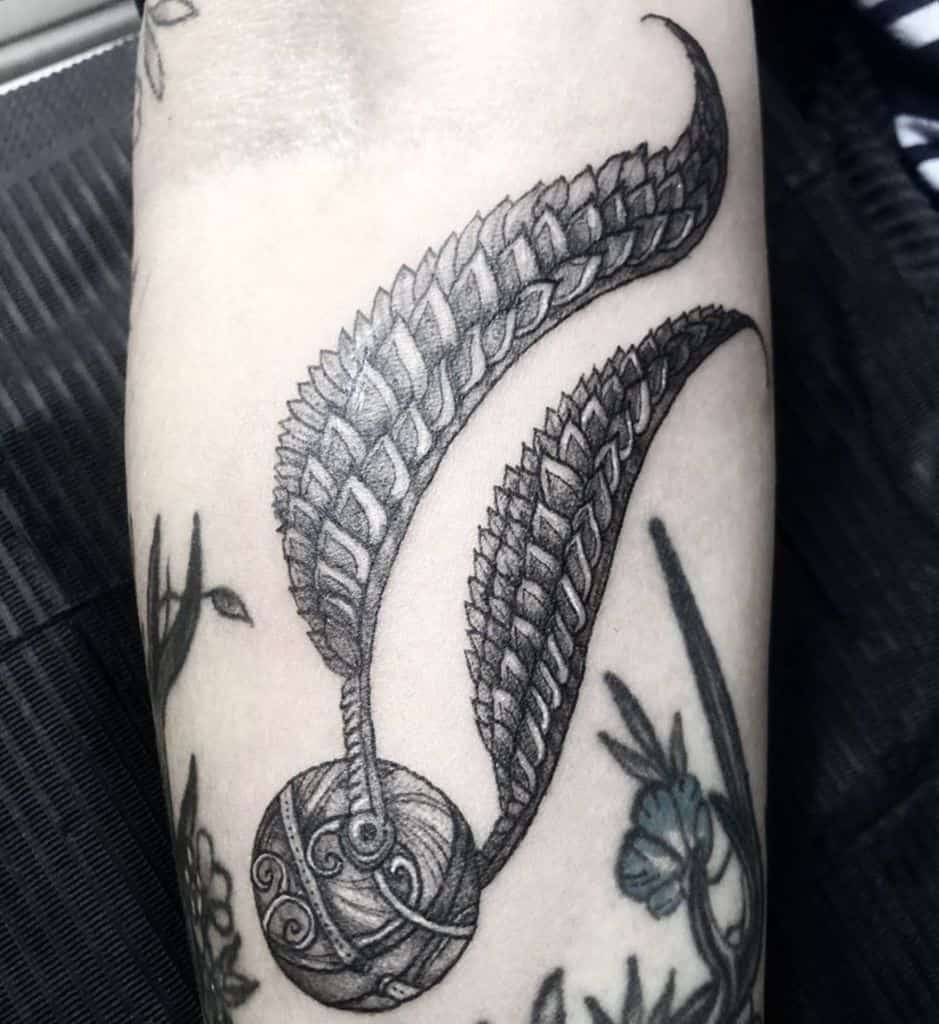 Intricate Golden Snitch tattoo with bold, feathered wings and ornate detailing, inspired by Harry Potter’s Quidditch game