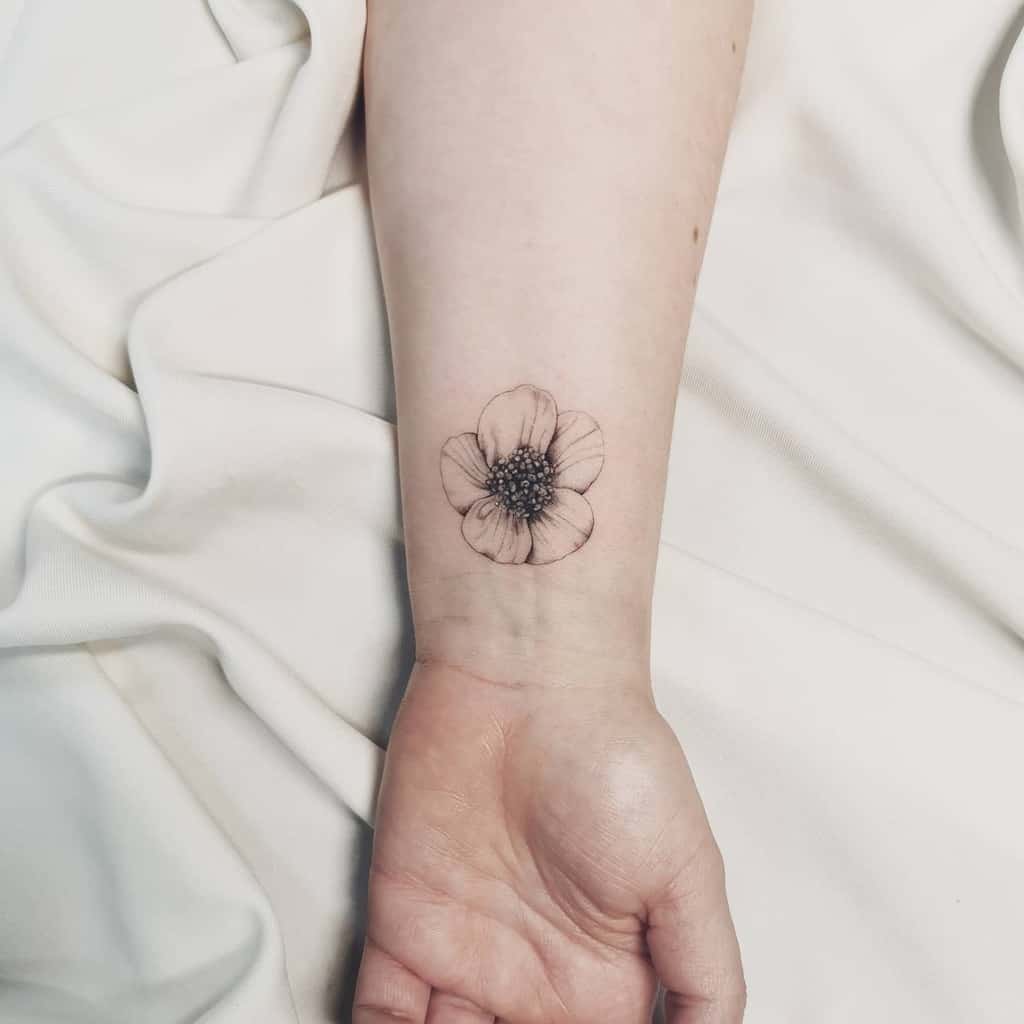 A delicate floral tattoo on the inner wrist against white fabric background