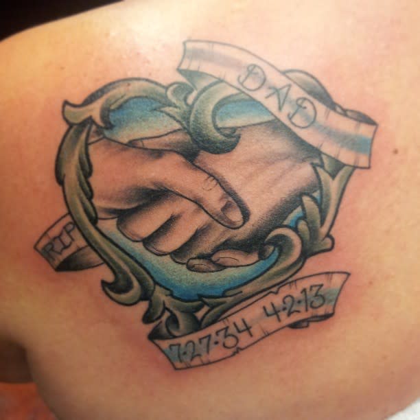 Tattoo of clasped hands inside a decorative frame with dates and initials on banners