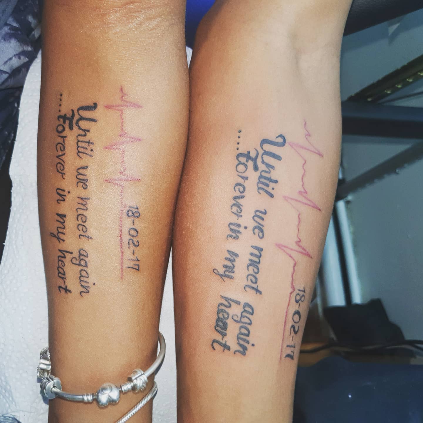 Two forearms with matching tattoos featuring the words "Until we meet again, forever in my heart"