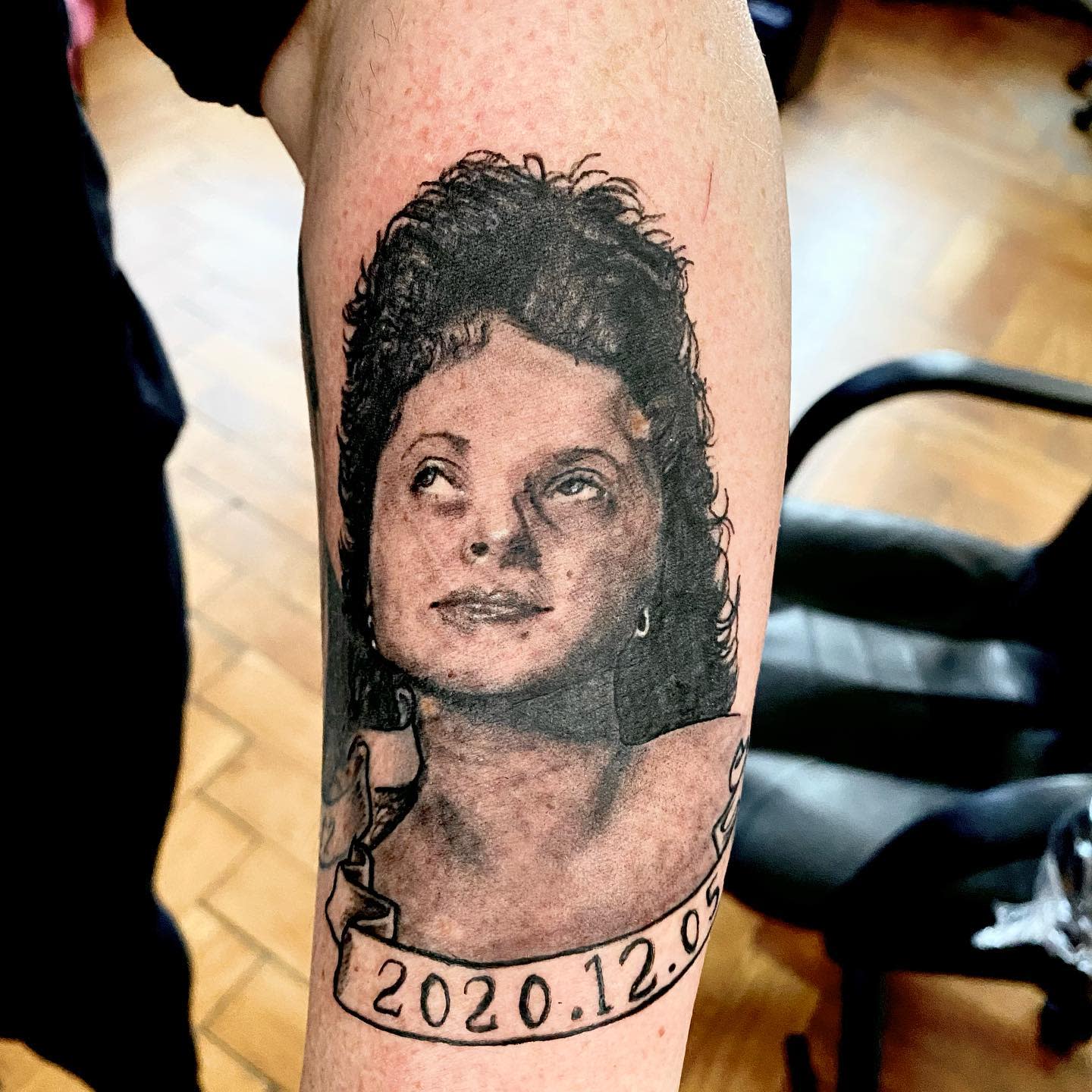 Memorial tattoo of a woman's face with a ribbon below displaying the date 2020.12.09