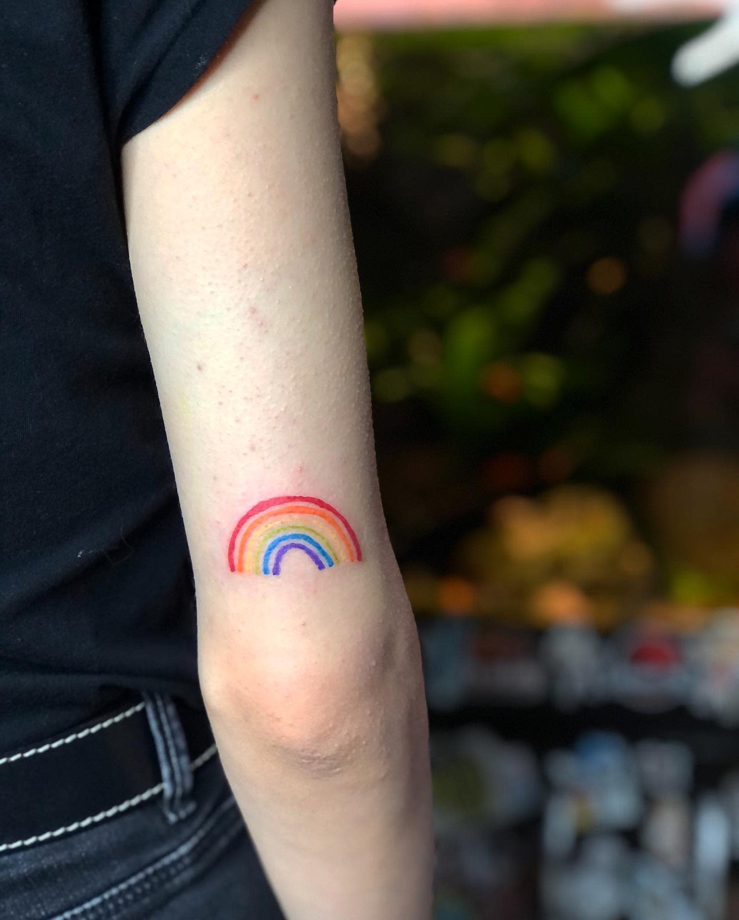 Showing a rainbow tattoo on the inner side of their arm