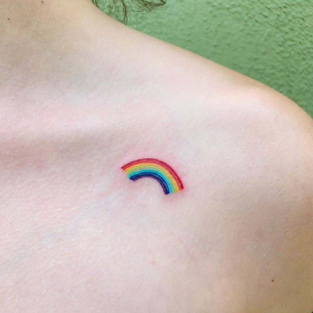 A colorful rainbow tattoo on the upper right shoulder