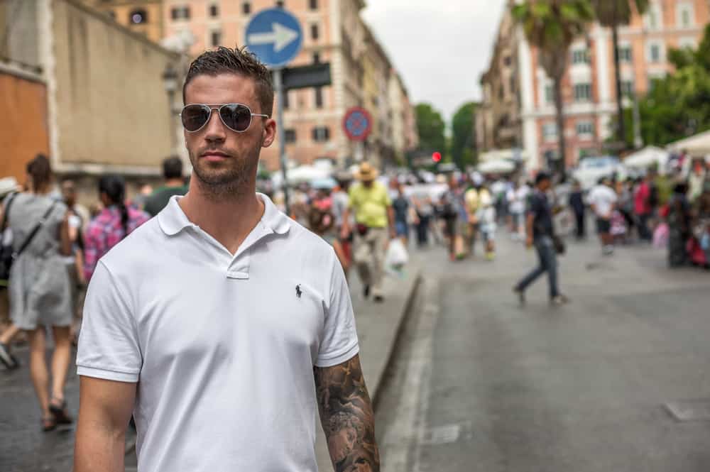 Man in a white Ralph Lauren polo and sunglasses on a street in Italy