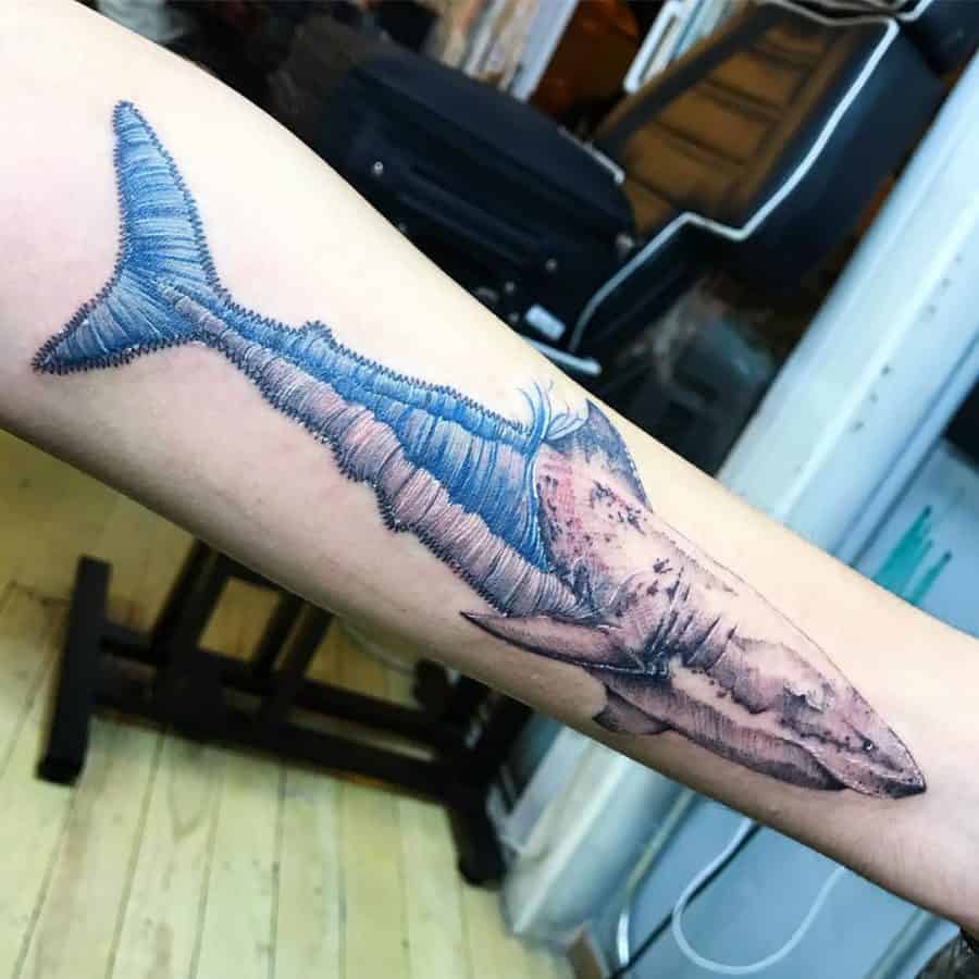 Artistic stitched shark tattoo with a patchwork tail effect, creating a fusion between embroidery and realism.