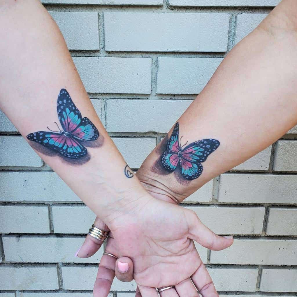 Two forearms with matching blue and pink butterfly tattoos
