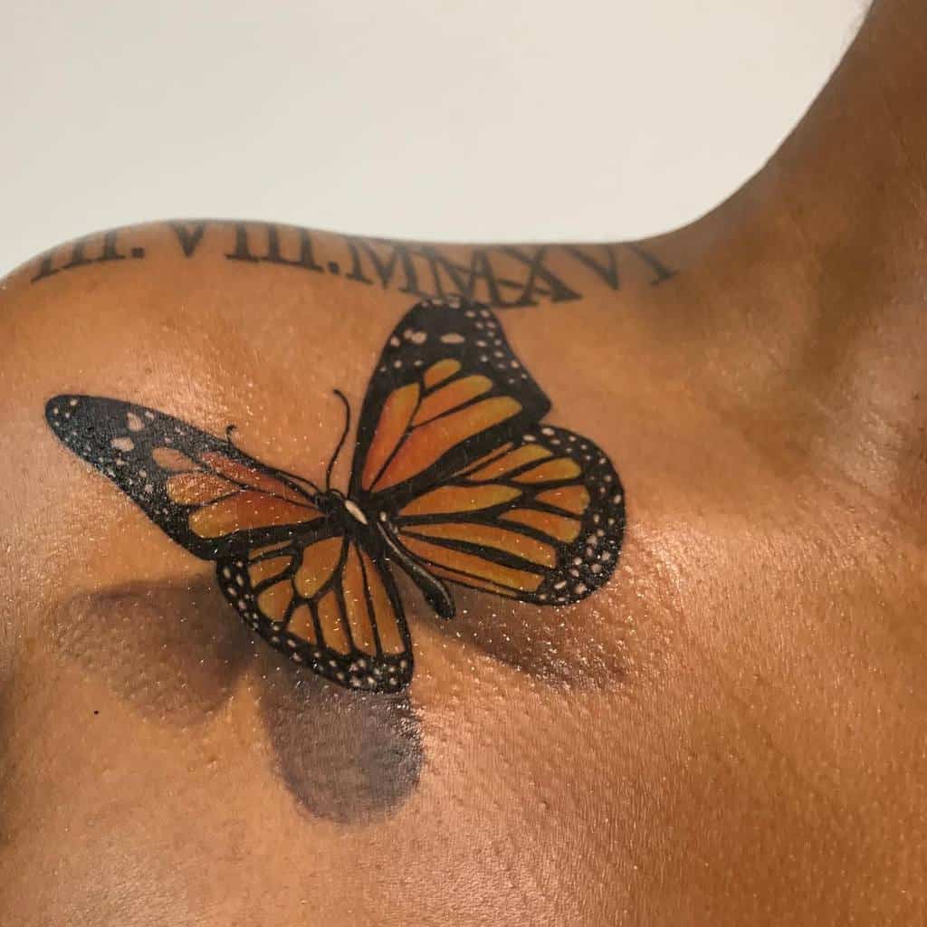 A realistic orange and black butterfly tattoo on a shoulder with Roman numerals above it