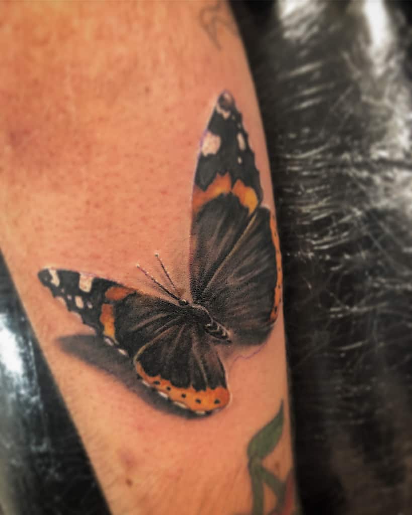 Realistic butterfly tattoo, featuring black, white, and orange wing patterns