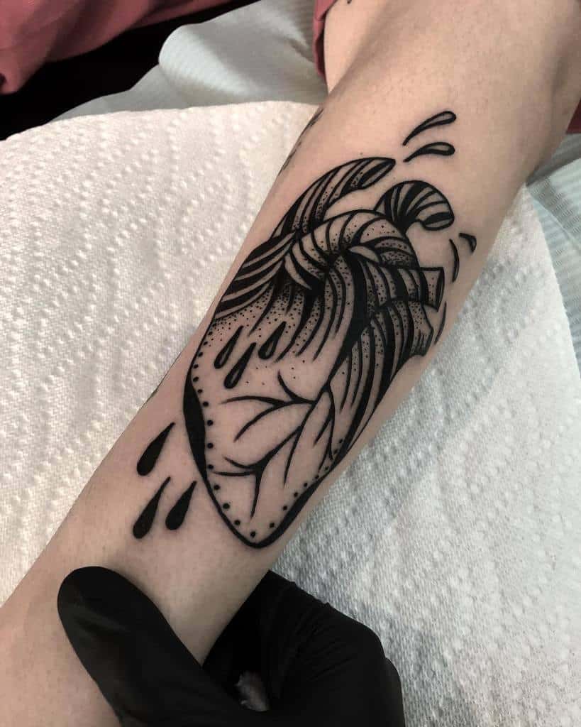 Tattoo of an anatomical black heart with leaves, black drops and abstract patterns
