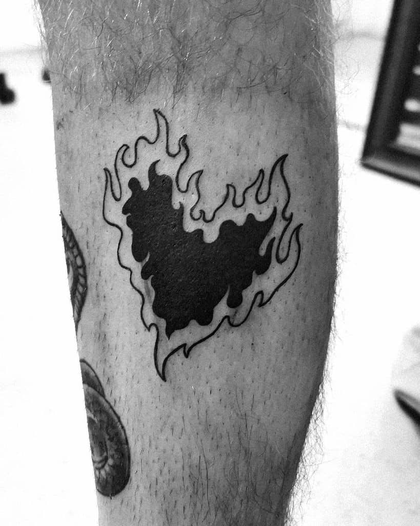 Bold black heart tattoo engulfed in dynamic flames, creating a fiery and intense design