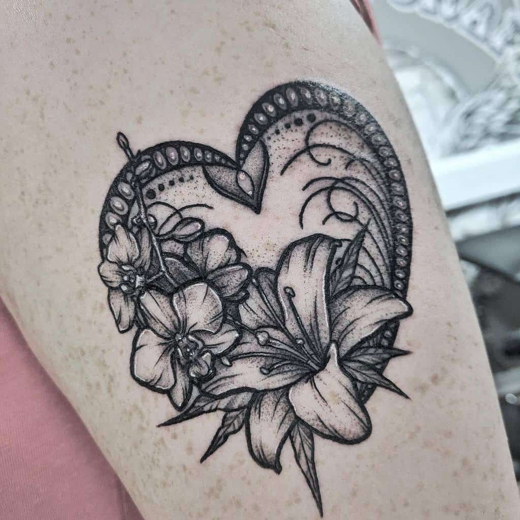 Detailed black tattoo of a heart adorned with paisley patterns and large, blooming flowers