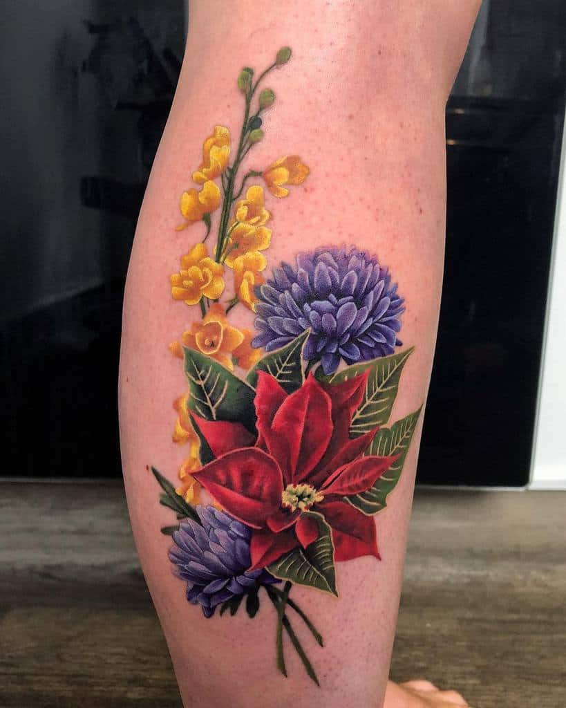 Colorful floral tattoo on the leg with a mix of aster, poinsettia, and yellow blossoms, symbolizing beauty and balance
