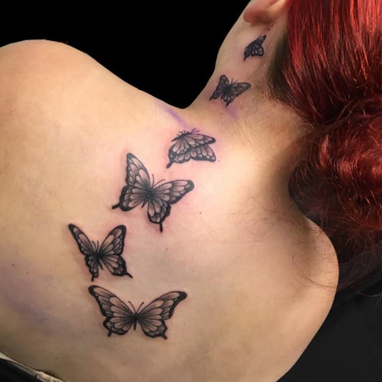 Woman with black butterfly tattoos on her neck and upper back