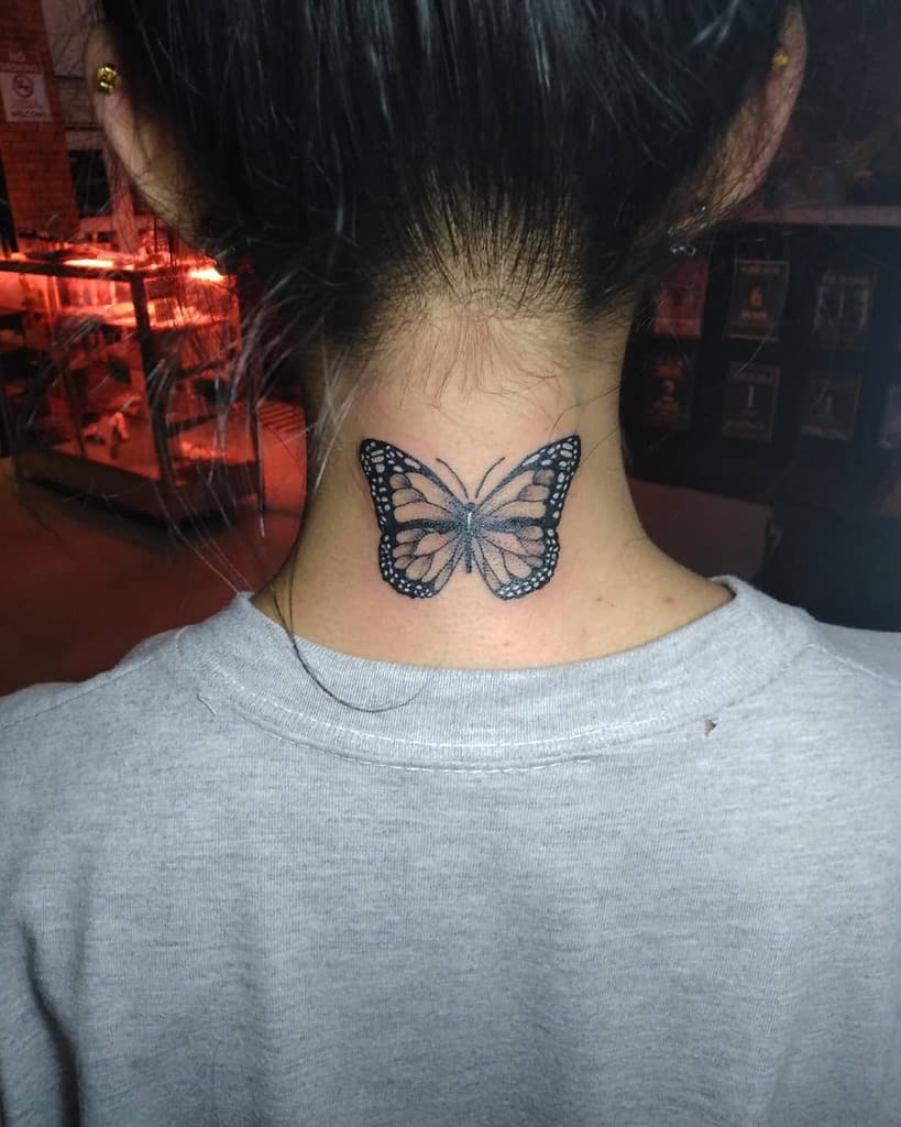 Black and white butterfly tattoo on the back of the neck