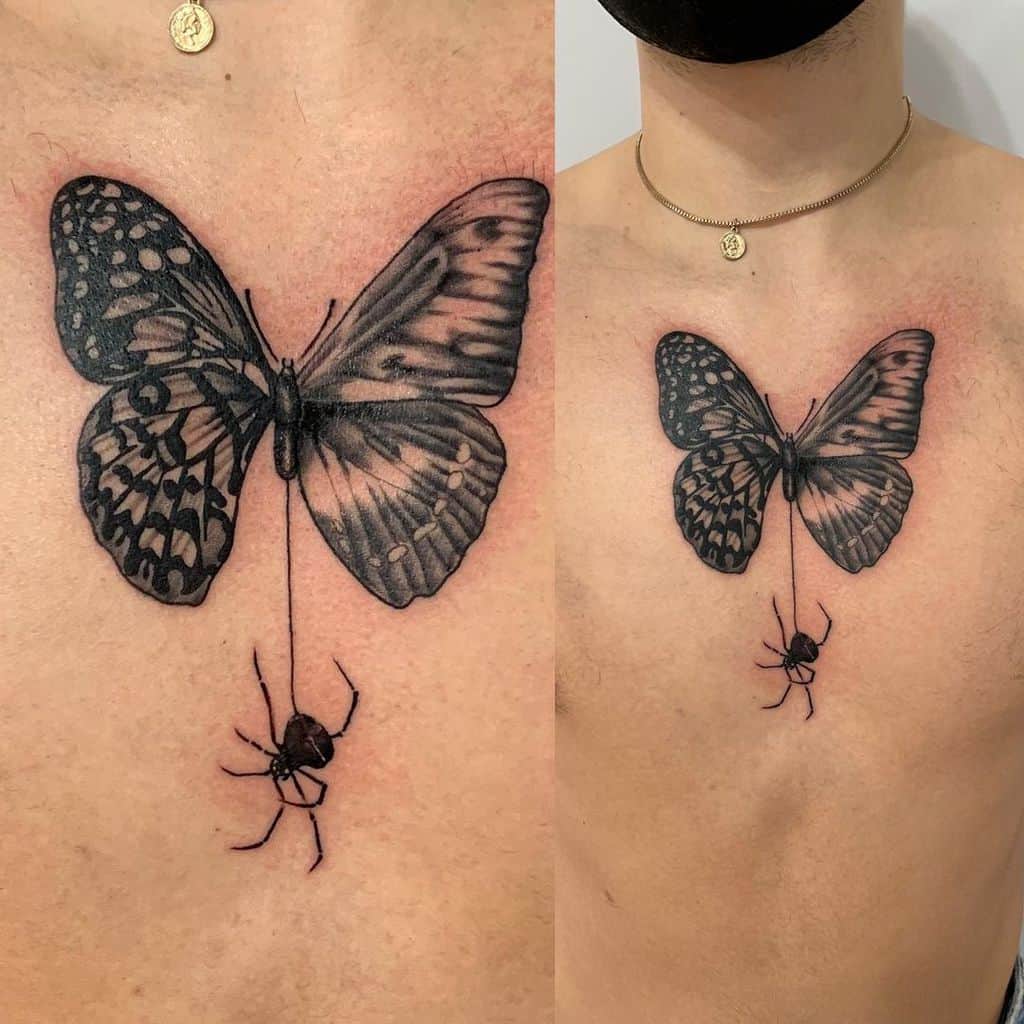 Chest tattoo of a black butterfly holding a dangling spider by a thread