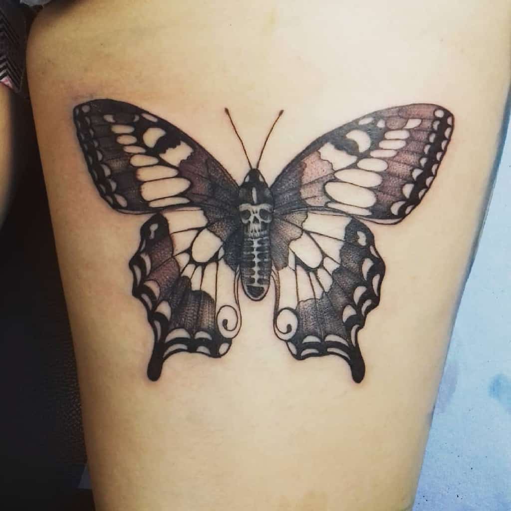 Tattoo of a large, detailed black butterfly with intricately patterned wings on skin