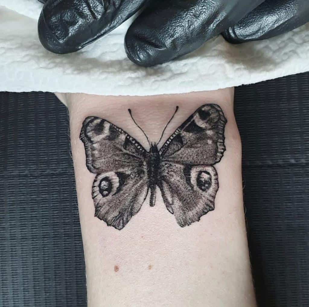 Black and grey butterfly tattoo on a wrist