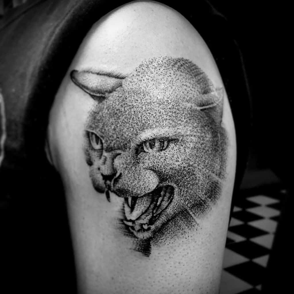 Arm tattoo of a snarling wild cat, showcasing detailed shading and stippling techniques to bring the fierce cat design to life