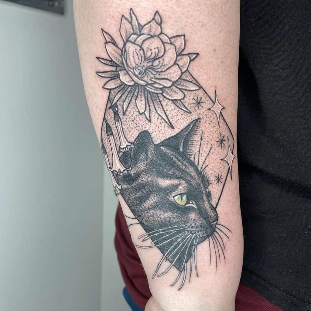 Tattoo of a sleek black cat with mesmerizing green eyes and a lotus flower gracefully inked on a person's arm