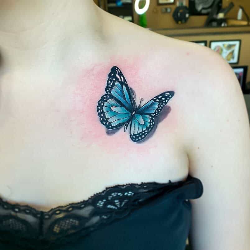 A delicate blue butterfly tattoo graces a woman's upper chest