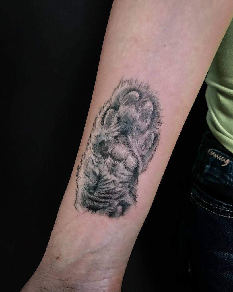 Close-up of a realistic cat paw print tattoo on a forearm