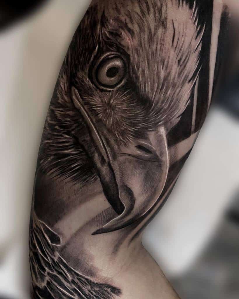 Close-up of an arm tattoo depicting a detailed, realistic black and white eagle's head