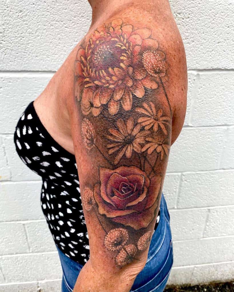 A stunning floral sleeve tattoo adorns the arm, beautifully interweaving roses and chrysanthemums
