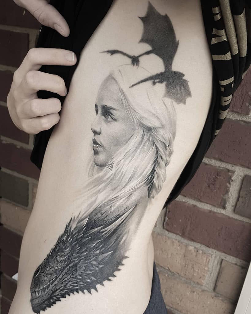 Realistic rib tattoo featuring Daenerys Targaryen's portrait with a dragon below and another flying above