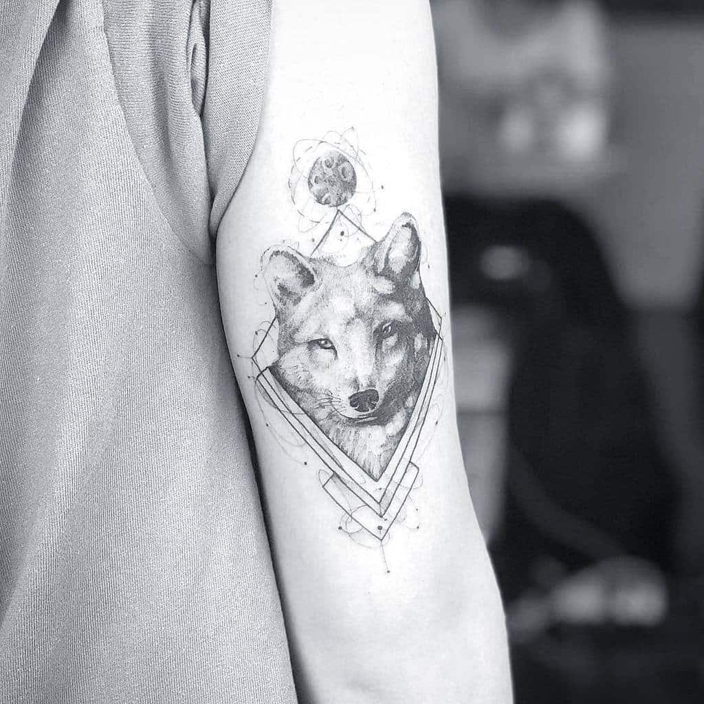 A detailed tattoo featuring a geometric fox design on an upper arm