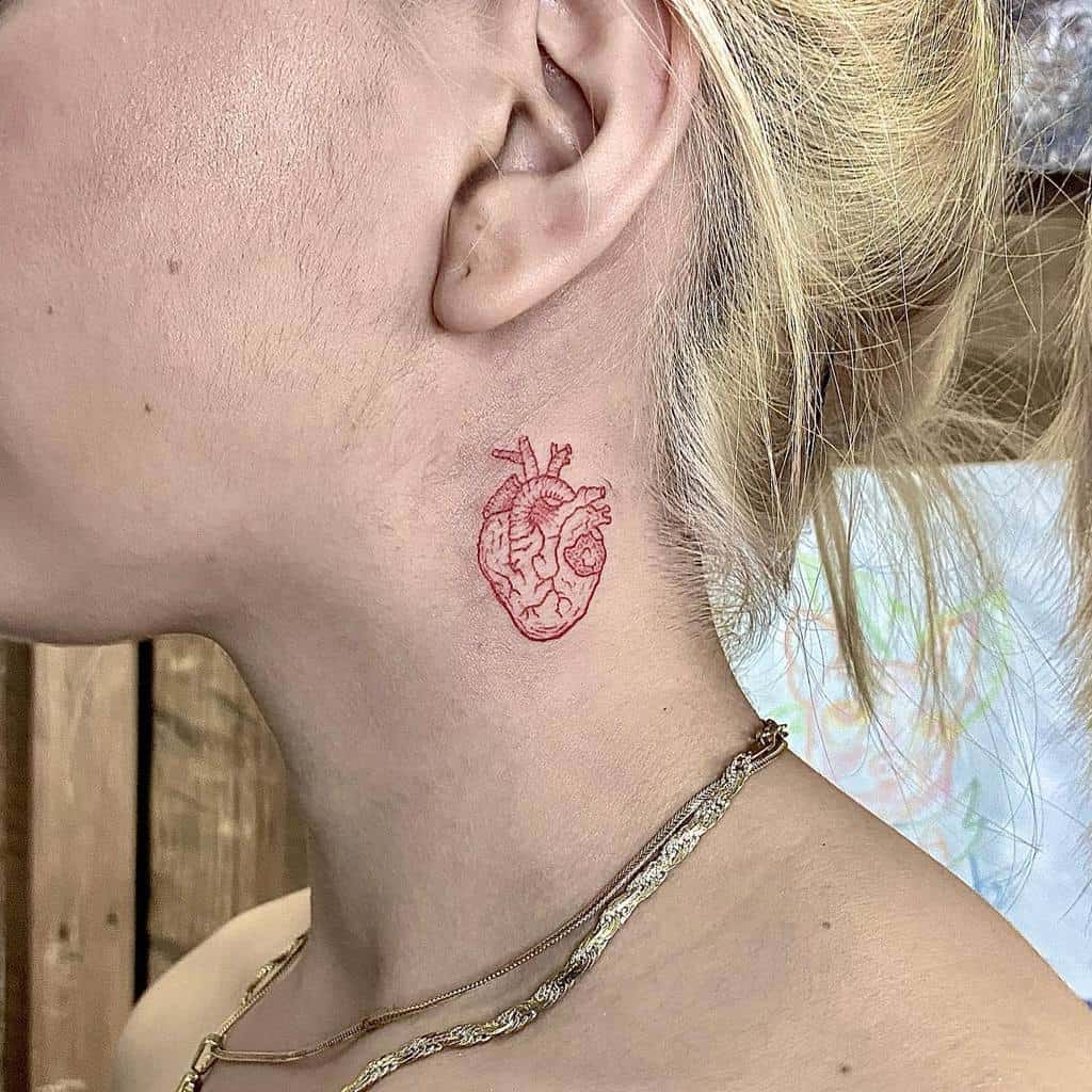 Small, red anatomical heart tattoo on the neck