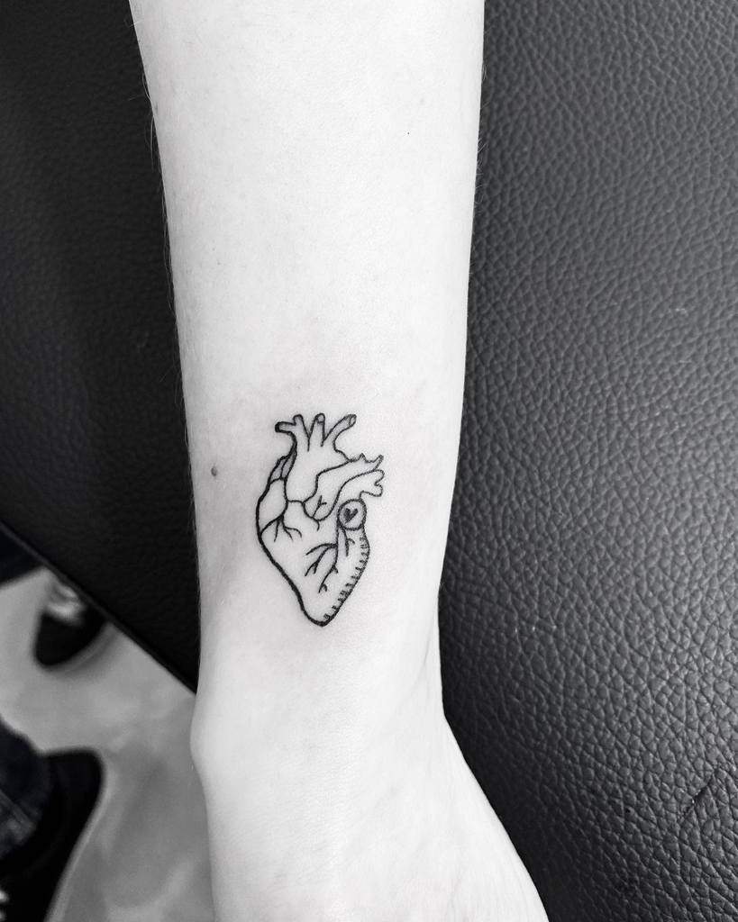 A tattoo of an anatomical heart on a person's inner forearm