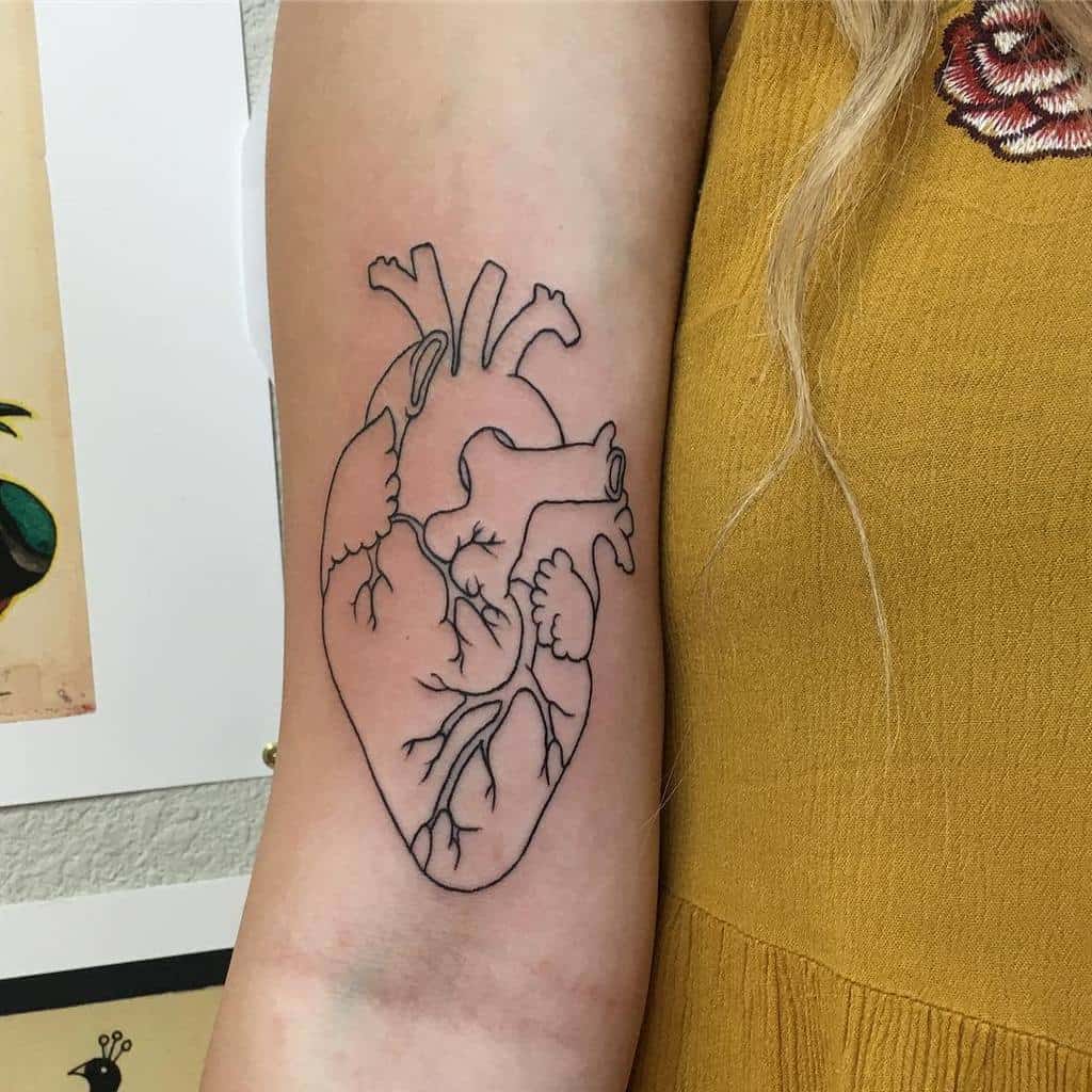 A woman's arm with an anatomical heart tattoo in black ink