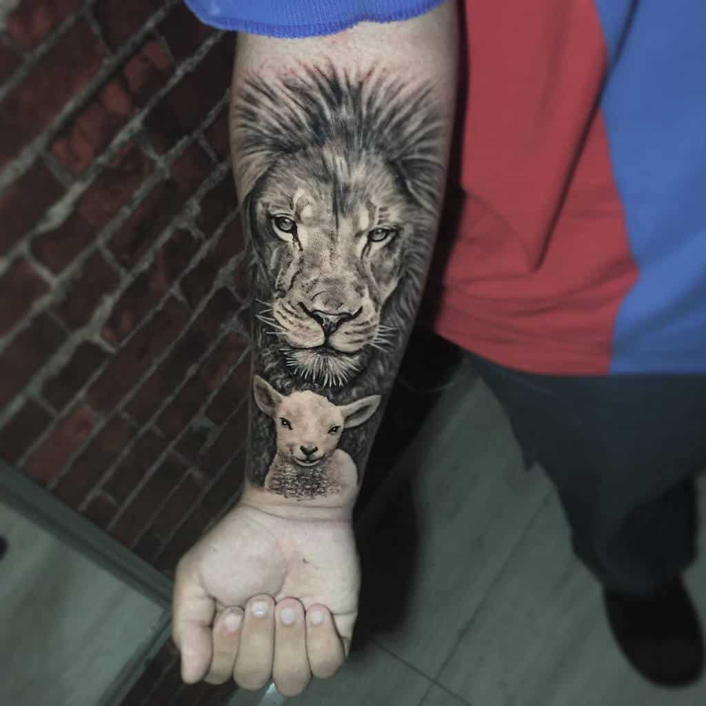 Forearm tattoo of a realistic lion's face above a lamb's face, set against a brick wall background