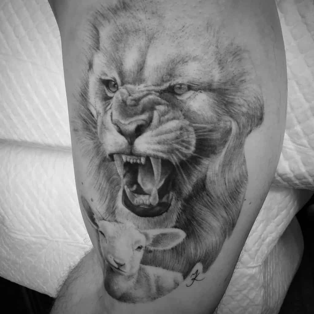 Black and white tattoo of a roaring lion above a calm lamb on a person's arm, striking a powerful balance