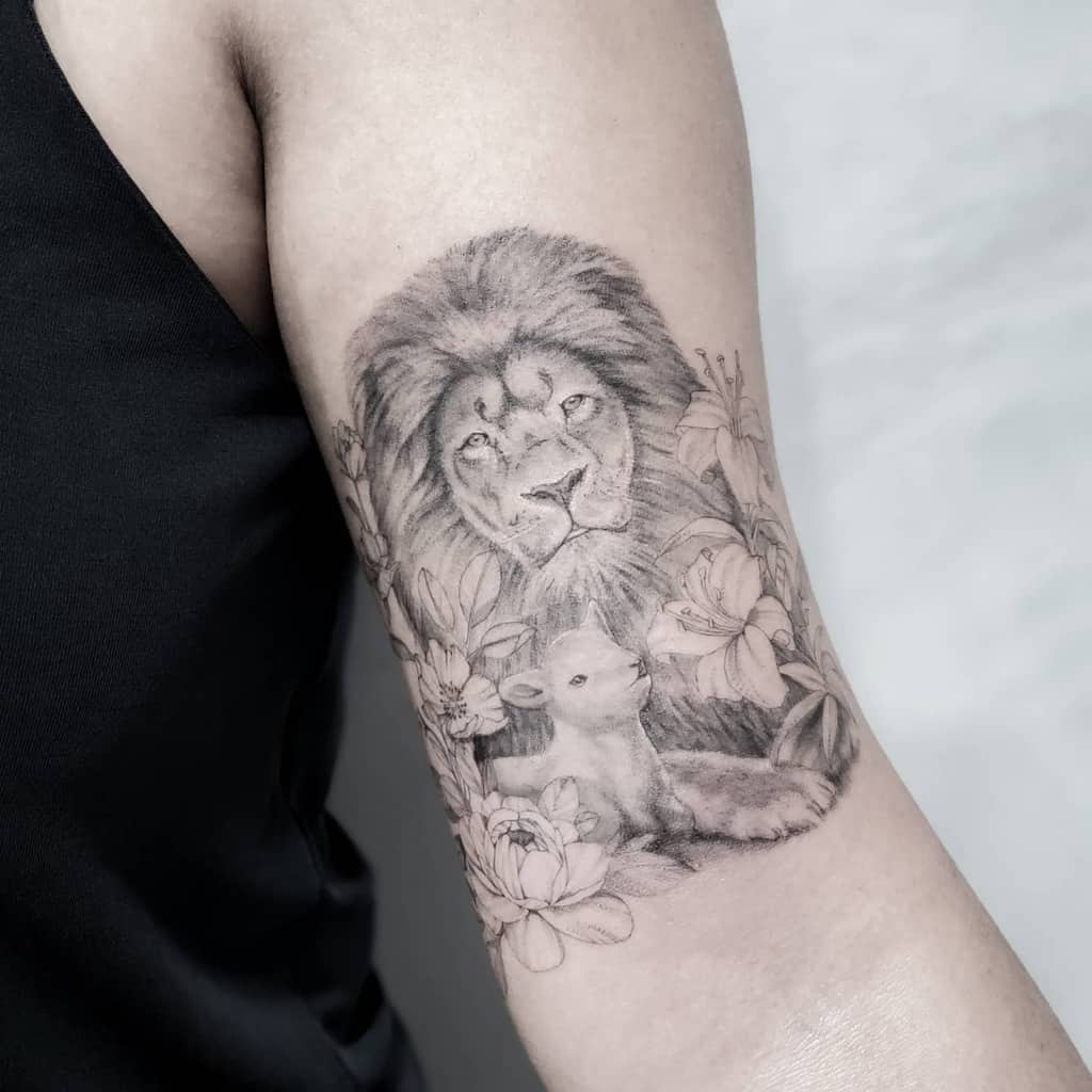 A stunning tattoo featuring a lion and lamb surrounded by flowers on an upper arm