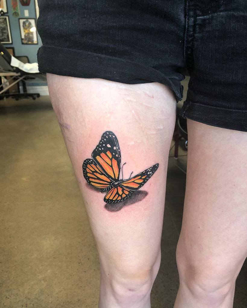 A lifelike monarch butterfly tattoo on the upper thigh