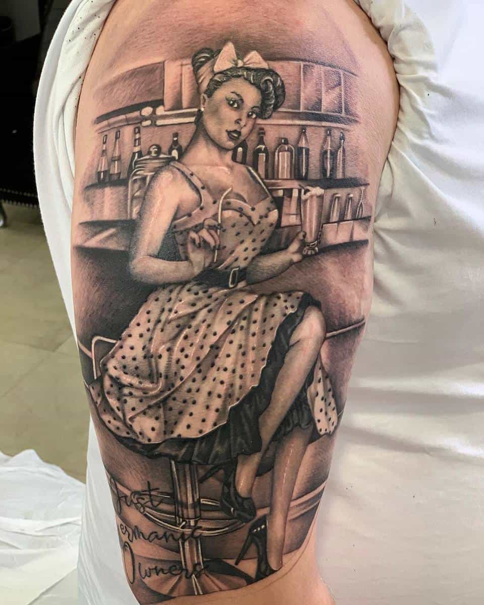 Tattoo of a pin-up girl in a 1950s diner setting on an arm, featuring a polka dot dress and retro hairstyle