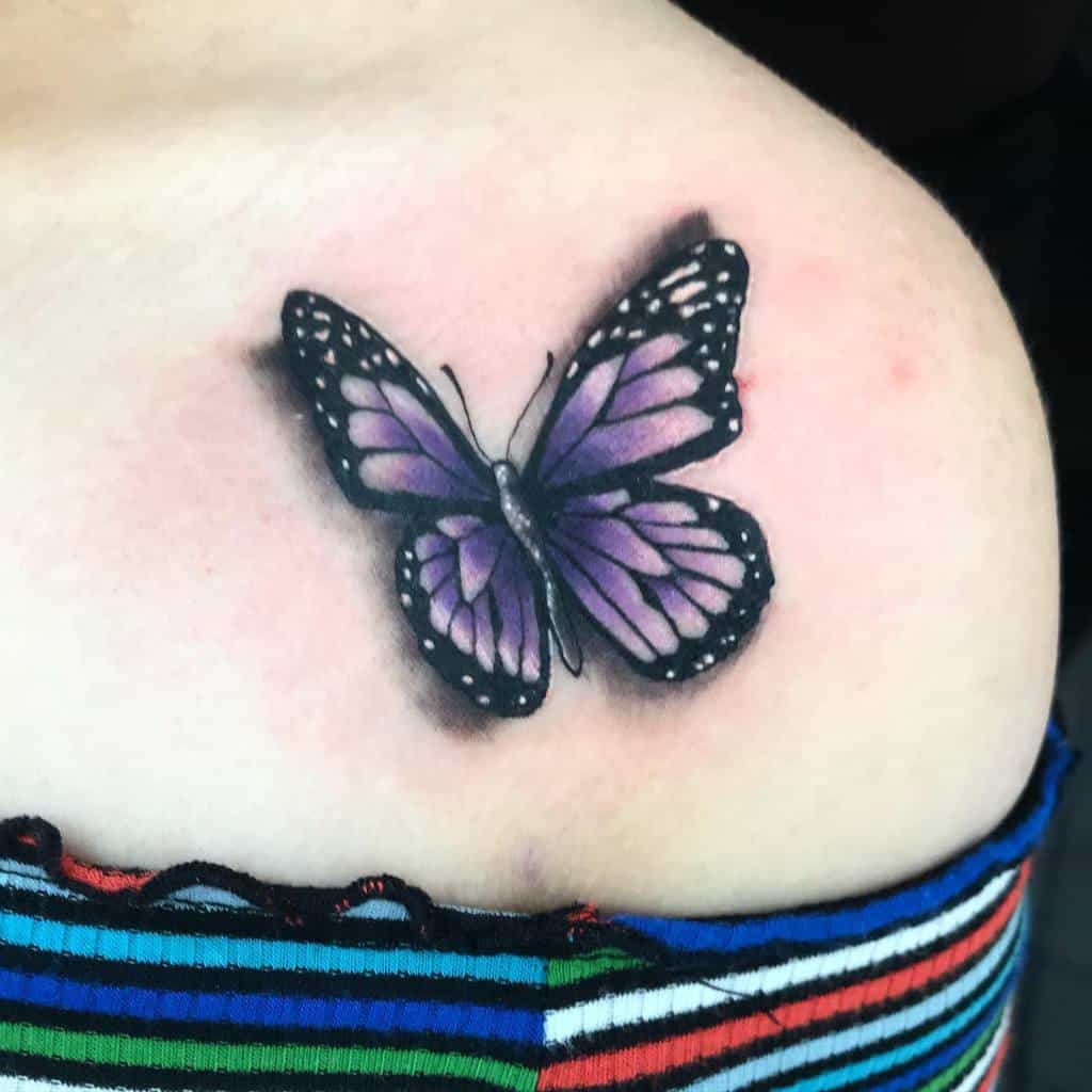 A tattoo of a purple butterfly on a shoulder