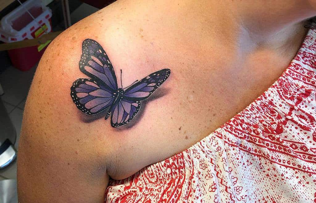 A realistic purple butterfly tattoo on a woman's shoulder