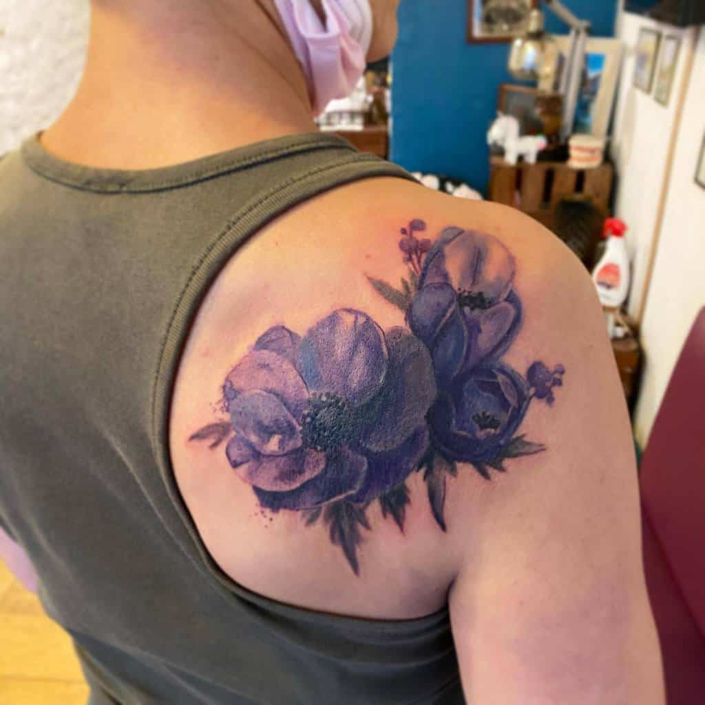 A man with a purple flower tattoo elegantly displayed on his shoulder