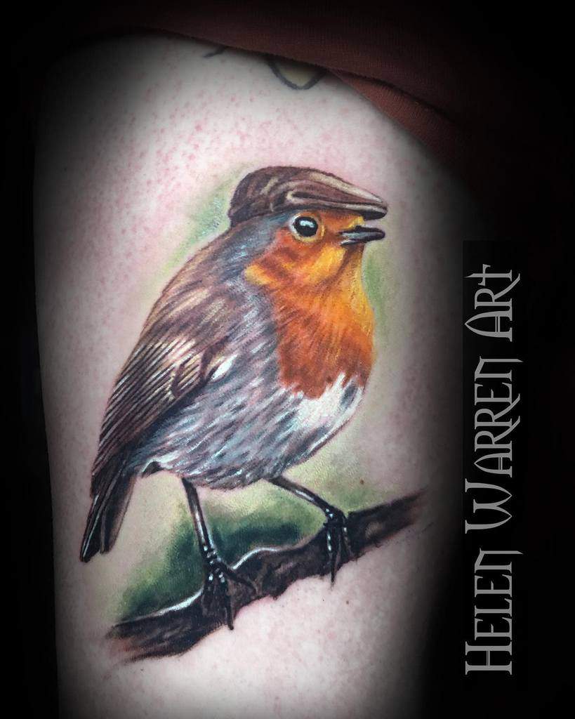 Colorful tattoo of a robin on a branch wearing a brown beret with green background