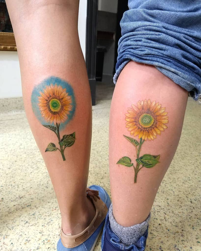 Two legs with matching sunflower tattoos, one surrounded by a blue circle