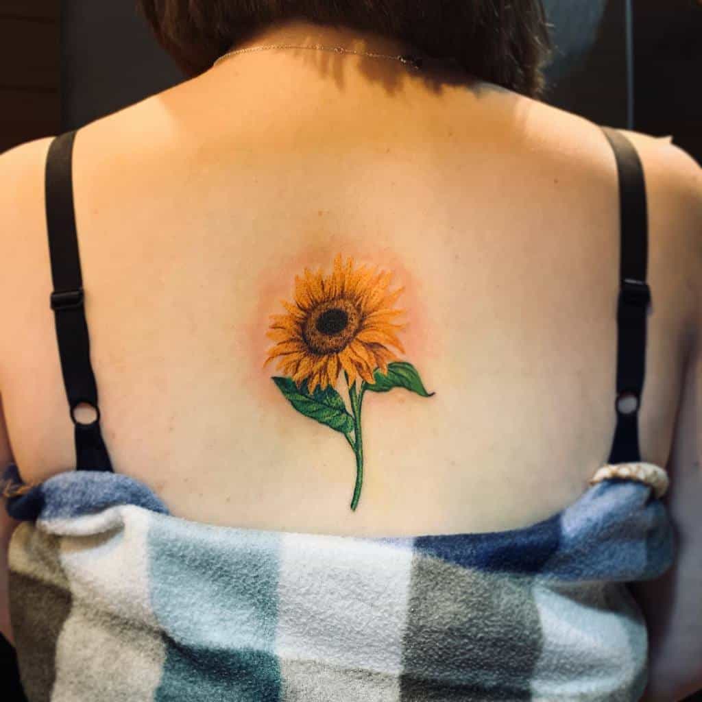 A woman's back with a sunflower tattoo